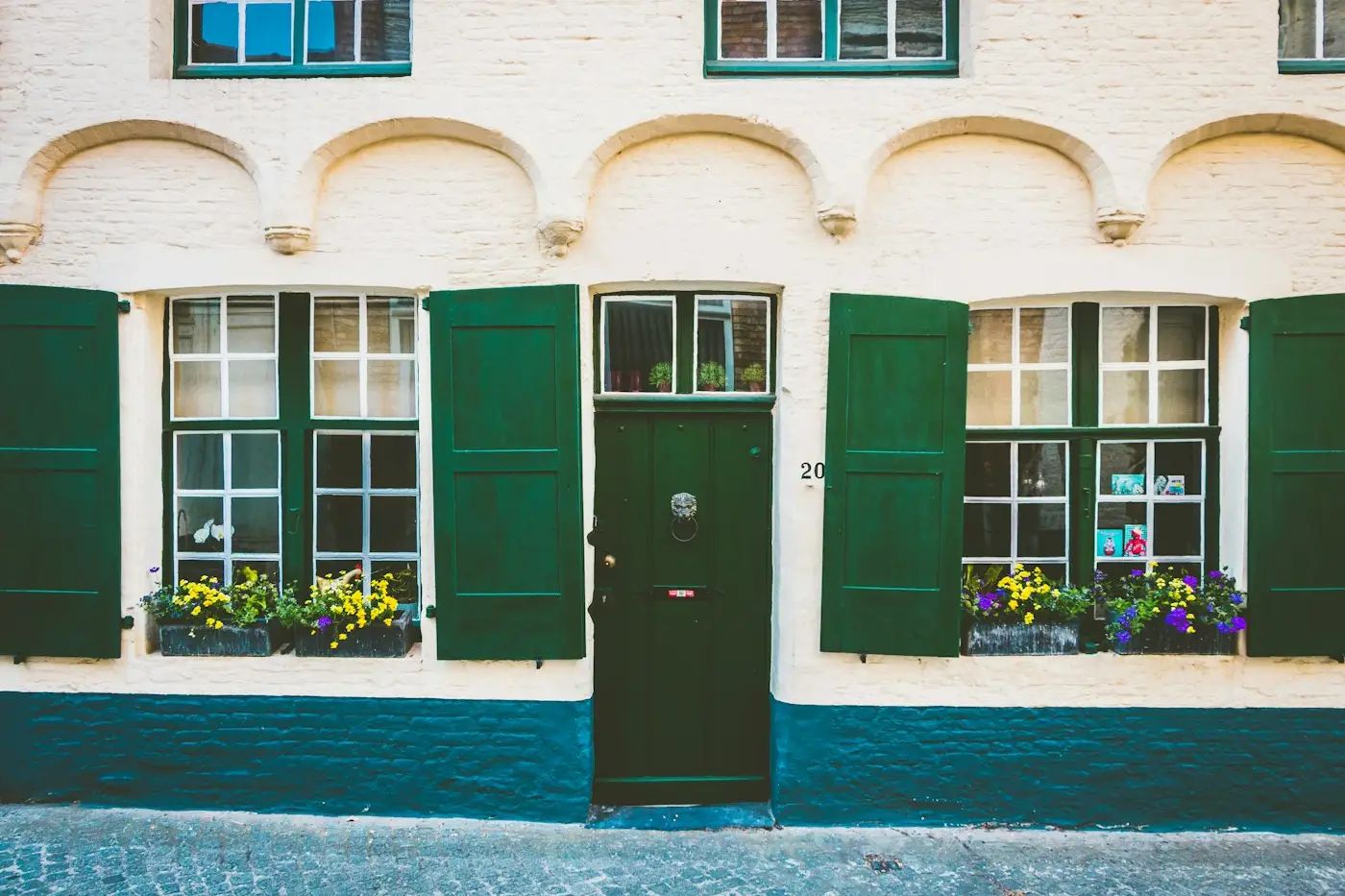 Frente pintado de una casa con ventanas verdes