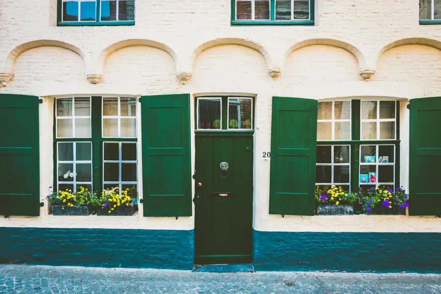Frente pintado de una casa con ventanas verdes