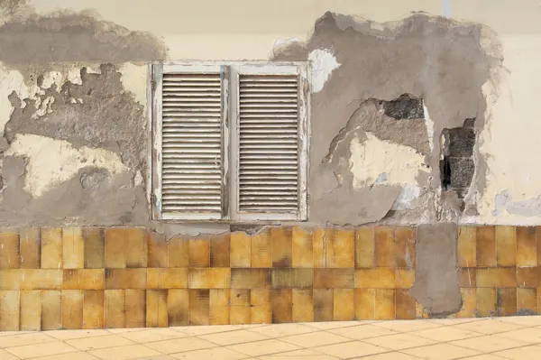 Pared con la pintura y el revoque caídos por humedad de cimientos