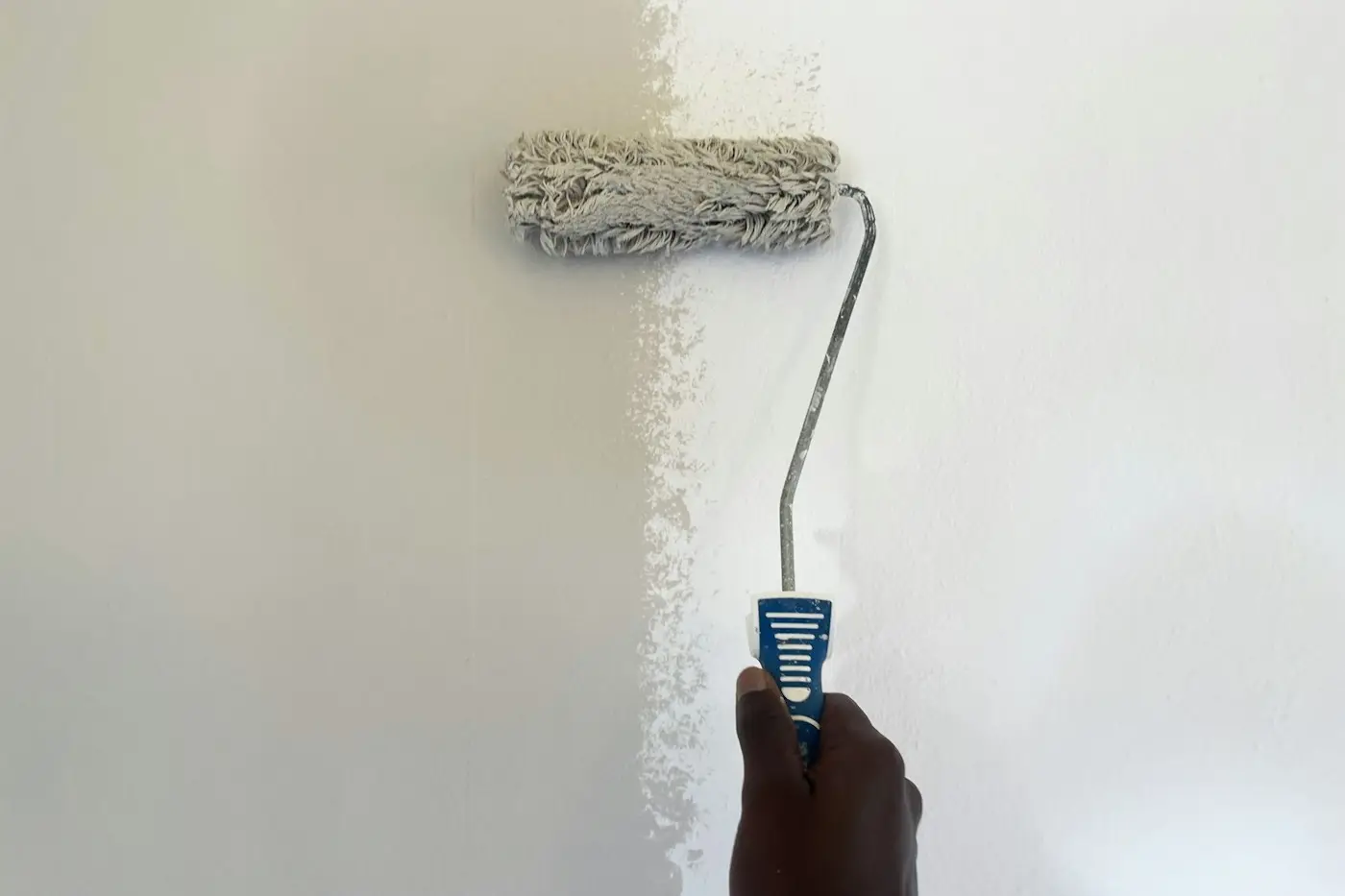 Rodillo pintando de blanco una pared interior
