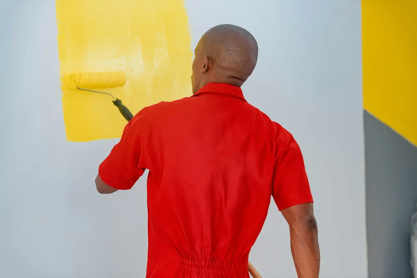 Pintor pintando una pared de amarillo con rodillo